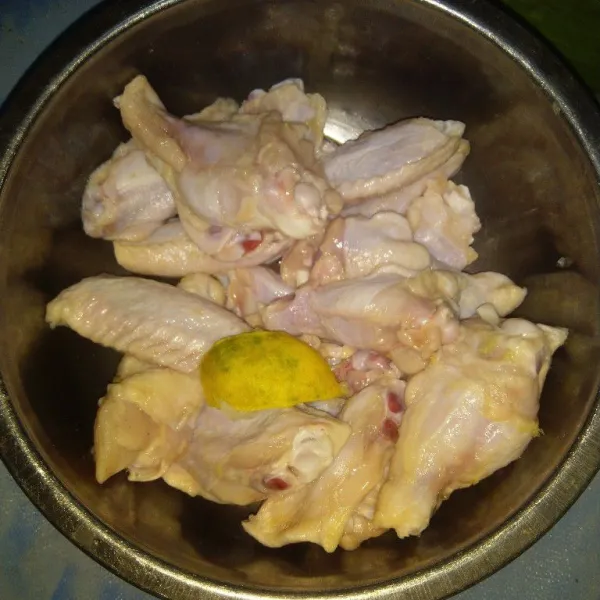 Cuci sayap ayam, potong-potong bagian persendiannya menjadi 2-3 bagian. Baluri dengan perasan jeruk nipis. Diamkan selama 15 menit kemudian cuci bersih. Tiriskan.