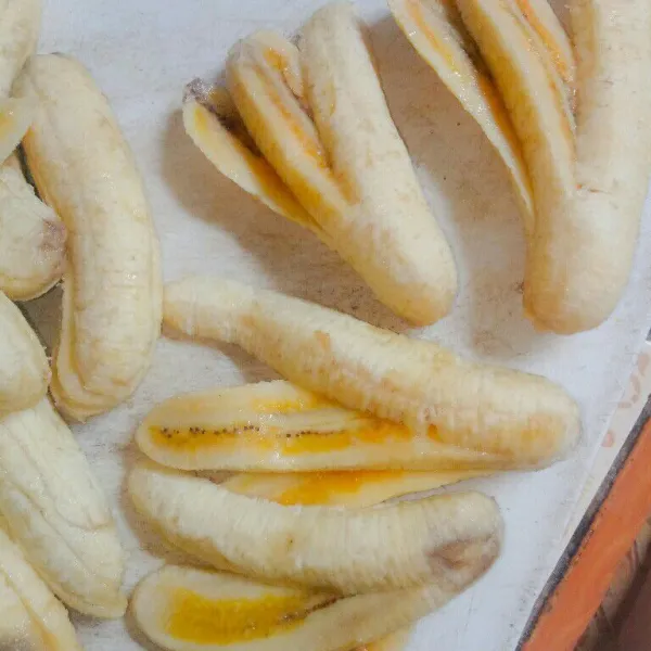Kupas kulit pisang, lalu iris pisang dengan bentuk kipas, jangan sampai putus irisannya.