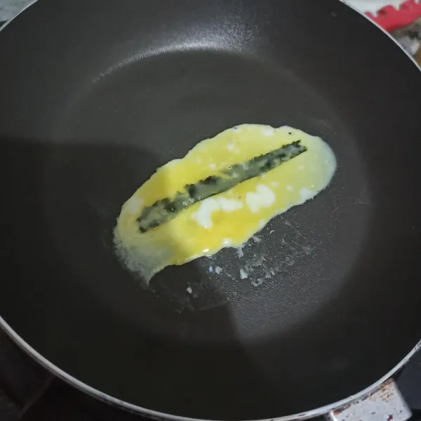 Olesi teflon dengan minyak/margarin. Panaskan teflon, beri selembar nori, lalu 1 sdm telur kocok.