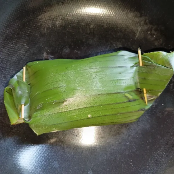 Kemudian bungkus ikan dan semat ujungnya dengan lidi.