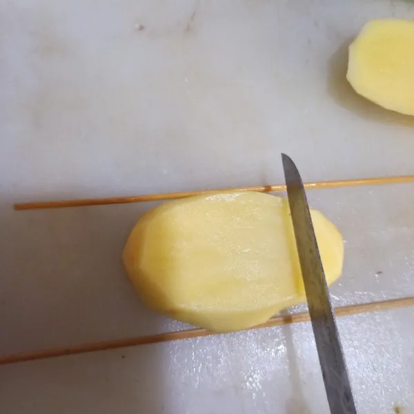 Tiriskan kentang, lalu iris dengan bantuan tusuk sate lurus seperti di gambar, iris tipis. Lalu balik, iris menyerong dengan disangga tusuk sate juga.