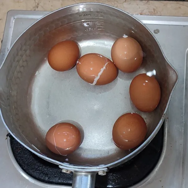 Rebus telur dalam air mendidih selama 12 menit di suhu tinggi hingga kuning telur mengeras (hard-boiled egg).