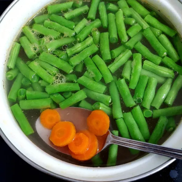 Masukkan wortel dan buncis ke dalam kuah sop.