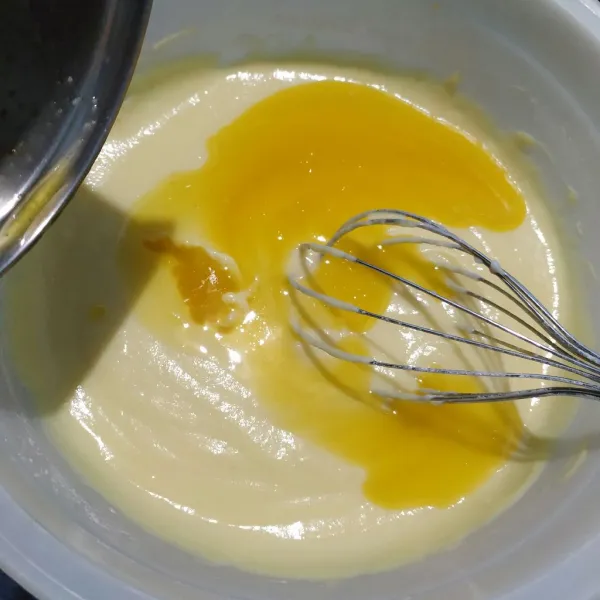 Masukkan mentega cair dan pewarna kuning, lalu aduk kembali hingga rata.