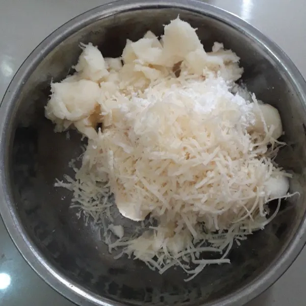 Masukkan parutan keju dan gula halus ke dalam wadah berisi tape. Uleni sampai tercampur rata.