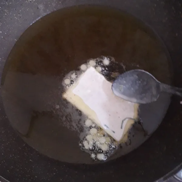 Masukkan tempe ke dalam adonan tepung lalu masukkan ke dalam minyak panas.