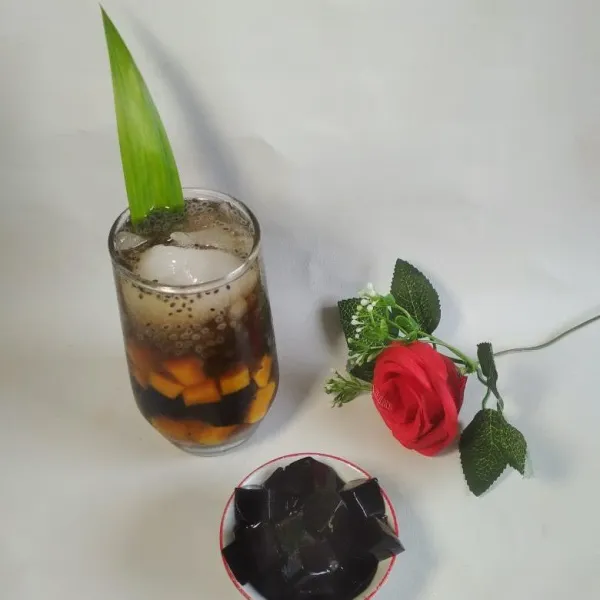 Siapkan gelas saji tata potongan mangga kweni, potongan cincau beri es batu dan tuang syrup gula merah beri selasih, sajikan segera