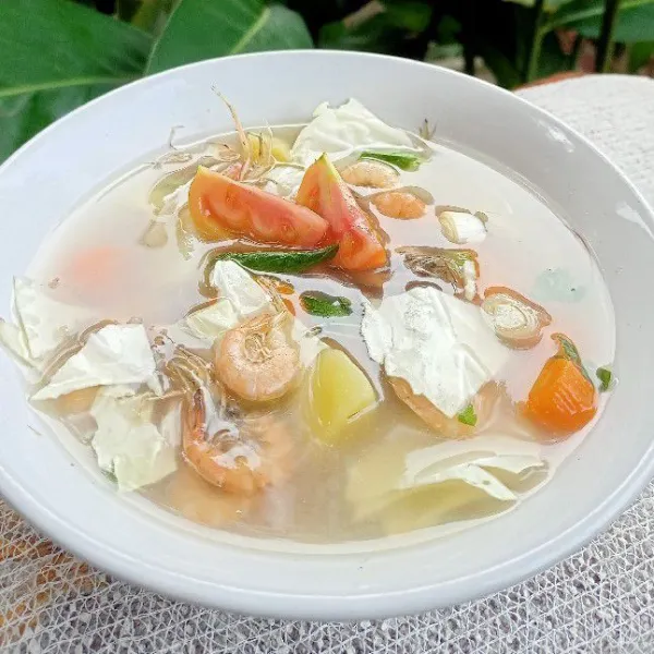 Setelah matang sajikan sayuran sop di atas mangkuk dengan tambahan kol putih, daun bawang, daun seledri, dan tomat.