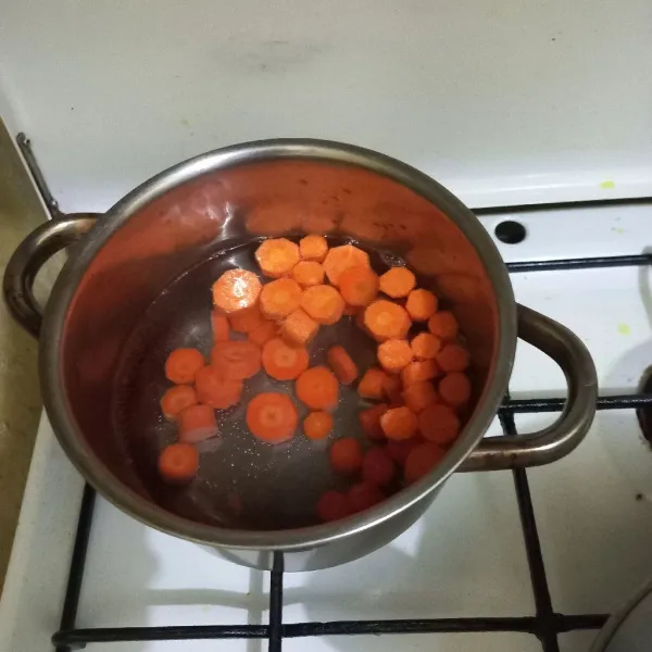 Didihkan air pada panci, masukkan irisan wortel masak hingga setengah matang.