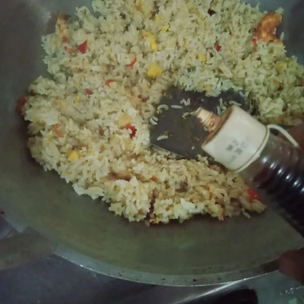 Masukkan kecap asin, aduk rata hingga nasi agak kering.