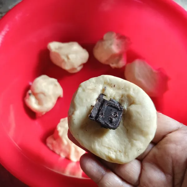 Kempiskan adonan dan bagi-bagi adonan, lalu isi dengan cokelat dan bentuk bulat.