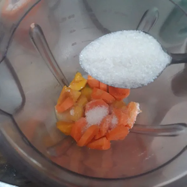 Masukkan potongan mangga dan wortel ke dalam blender. Tambahkan susu kental manis dan gula pasir.
