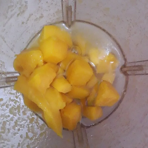 Kupas dan potong potong buah mangga. Masukkan ke dalam blender. Tambahkan air secukupnya. Blender sampai halus.