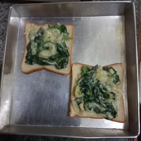 Tata roti pada loyang, tuang adonan bayam di atasnya, ratakan.