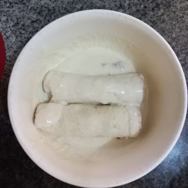 Celupkan gulungan roti pada adonan tepung, ratakan.