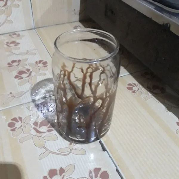 Tuang susu kental manis cokelat ke dalam gelas.