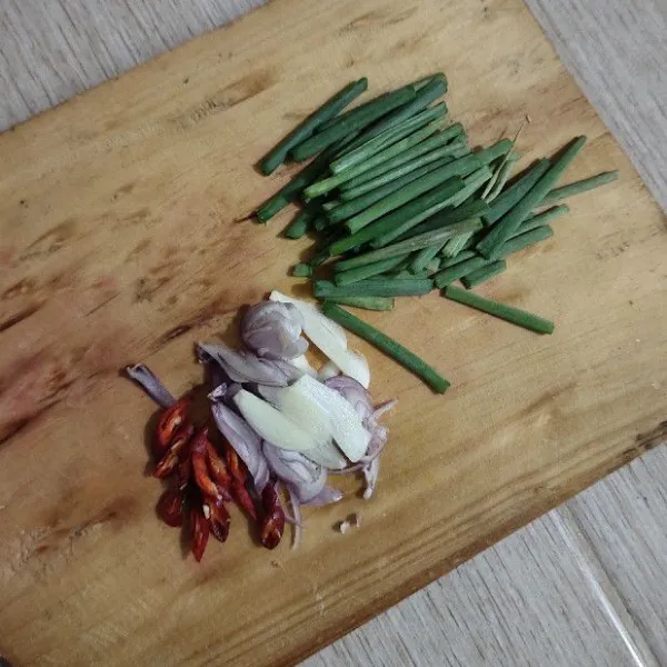 Iris-iris daun bawang merah, bawang putih, bawang merah dan cabe keriting.