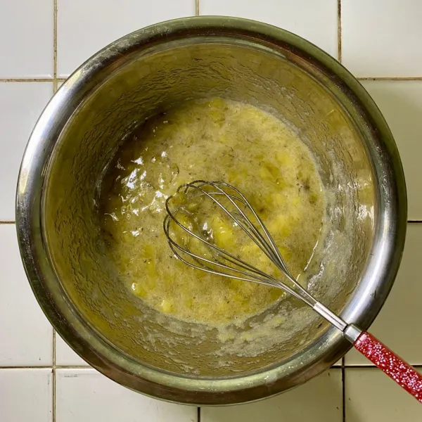 Haluskan pisang menggunakan whisk, lalu sisihkan.