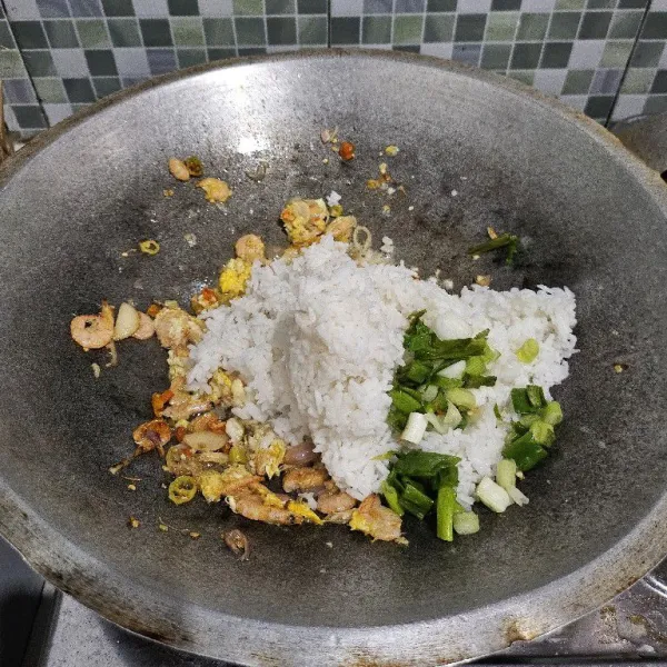 Masukkan nasi putih dan daun bawang, aduk rata.