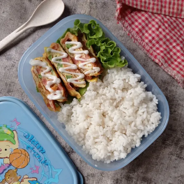 Potong potong tamago, tata pada kotak bekal, lalu beri nasi juga, sajikan.