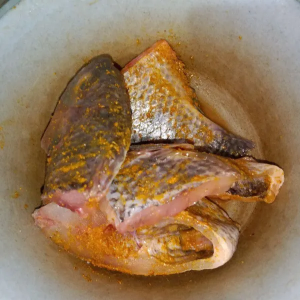 Cuci bersih ikan dan bumbui dengan bumbu ikan goreng instan.