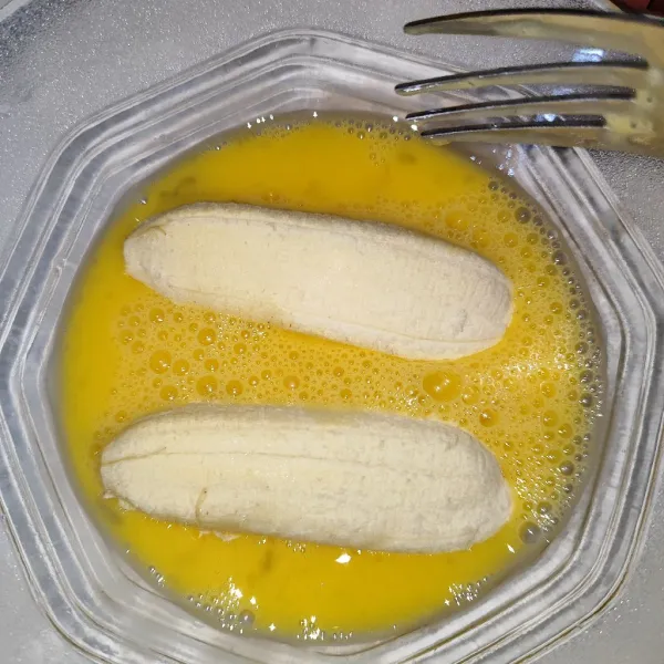 Kocok lepas telur lalu kupas pisang dan gulirkan ke dalam telur.