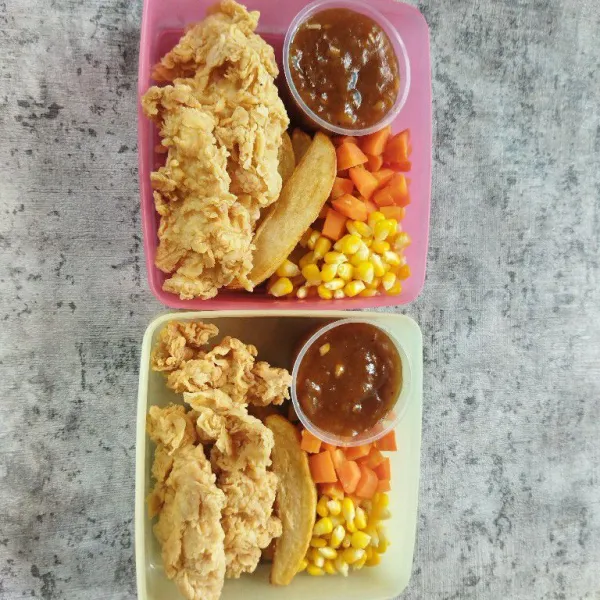 Tata ayam krispi, kentang goreng, sayuran rebus dan saus dalam wadah bekal.