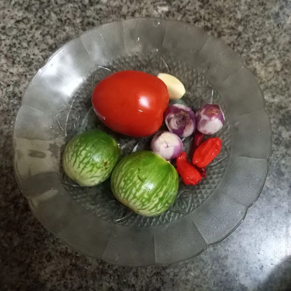 Kupas bawang merah, bawang putih, terong dan tomat.