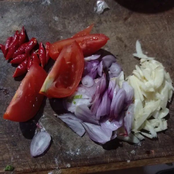 Iris bawang merah, tomat, dan cabai lalu cincang juga bawang putih.