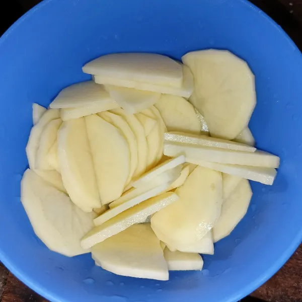 Kupas kentang dan iris tipis, kemudian cuci bersih.