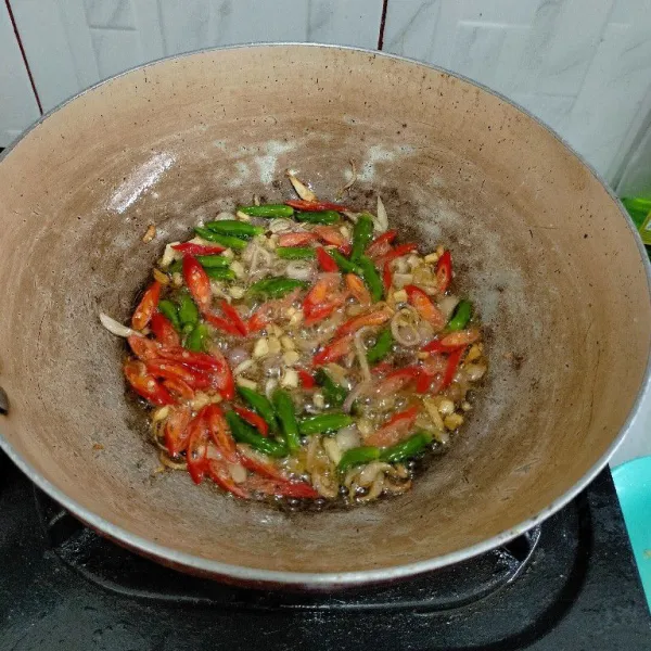 Tumis bawang merah dan bawng putih lalu masukan cabe merah dan rawit utuh.