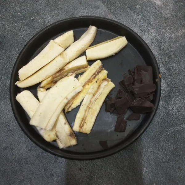Kupas pisang lalu potong jadi 4 bagian perpisangnya. Potong-potong dark cooking chocolate.