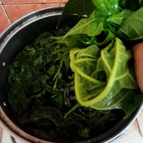 Didihkan air dan rebus daun pucuk singkong dan pepaya, masak hingga layu.