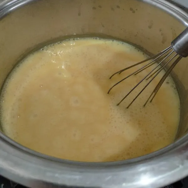 Masukan bubuk jelly mangga, gula pasir, dan tepung maizena kedalam wajan lalu tuang susu cair dan air aduk hingga tercampur rata. Masak dengan api sedang sambil di aduk terus sampai mendidih.