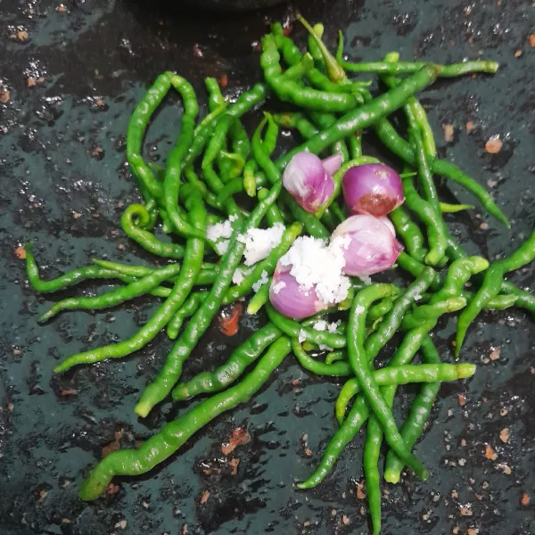 Cuci bersih cabe hijau dan bawang merah, lalu masukkan ke dalam batu. Tambahkan garam.