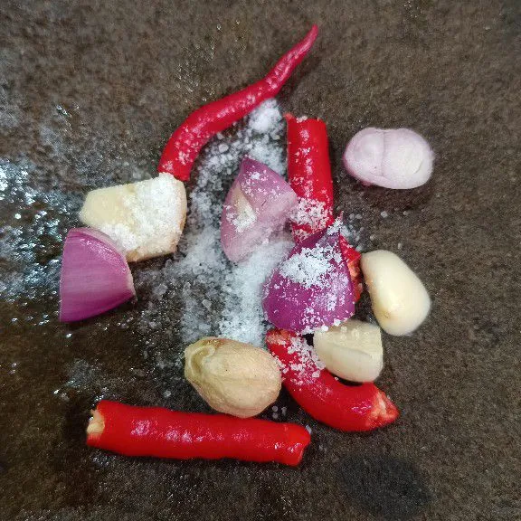 Haluskan bawang merah, bawang putih, cabe keriting, kemiri dan garam hingga halus.