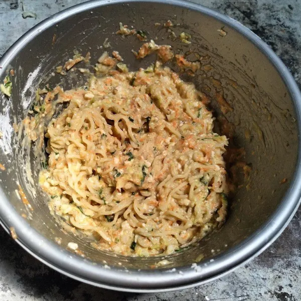 Campurkan mie beserta bumbu instannya, wortel, daun bawang, ayam, telur, tepung tapioka dan garam ke dalam wadah. Aduk rata semua bahan.