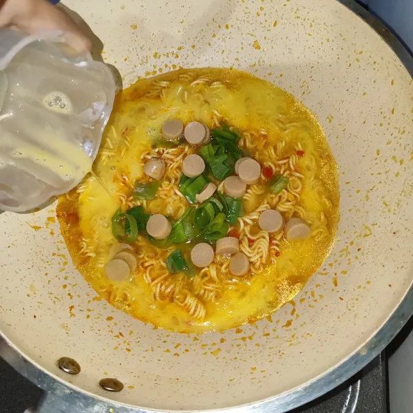 Lalu kocok lepas telur dan masukkan ke dalam wajan kemudian masukkan daun bawang dan irisan sosis.