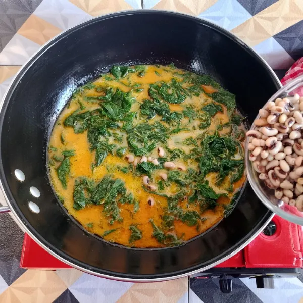 Masukkan daun singkong dan kacang tolo, masak hingga mendidih dan daun singkong lunak.