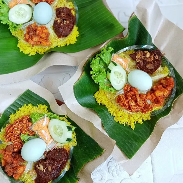 Sajikan nasi kuning di atas cobek dengan aneka lauk, telur asin, mentimun, selada dan serundeng.