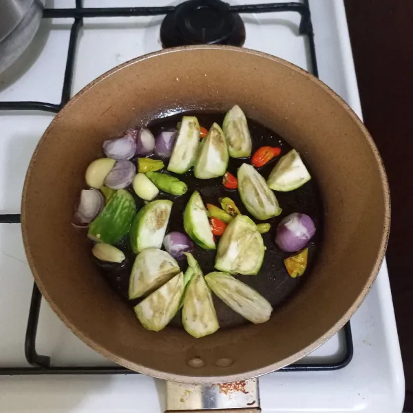 Masukkan bawang merah, bawang putih, potongan terong, cabe rawit dan terasi bakar ke dalam wajan dengan minyak goreng secukupnya.