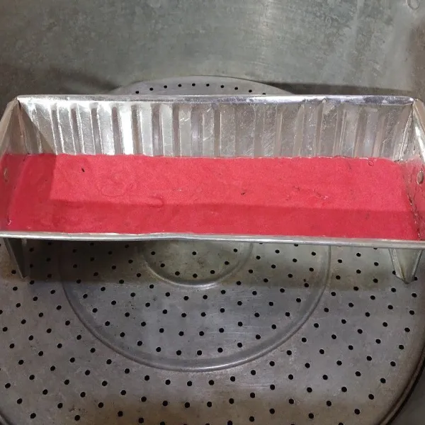Masukkan adonan merah ke loyang yang sudah diolesi minyak goreng. Kukus dengan api sedang cenderung kecil selama 5 menit. Tutup kukusan dibungkus kain agar air tidak menetes ke kue.