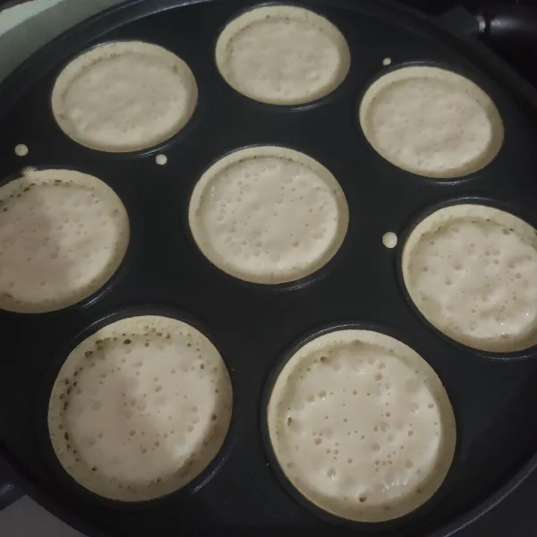 Panaskan teflon atau cetakan martabak mini api sedang, tuang satu sendok sayur lalu putar-putar, diamkan hingga berlubang kemudian tutup, jika sudah matang atau adonan sudah tidak basah angkat.