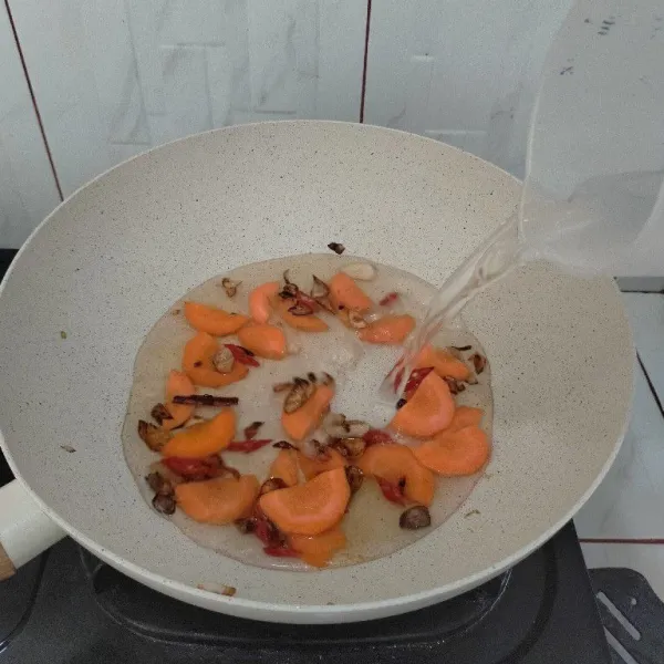 Masukkan wortel dan air, lalu masak hingga mendidih.