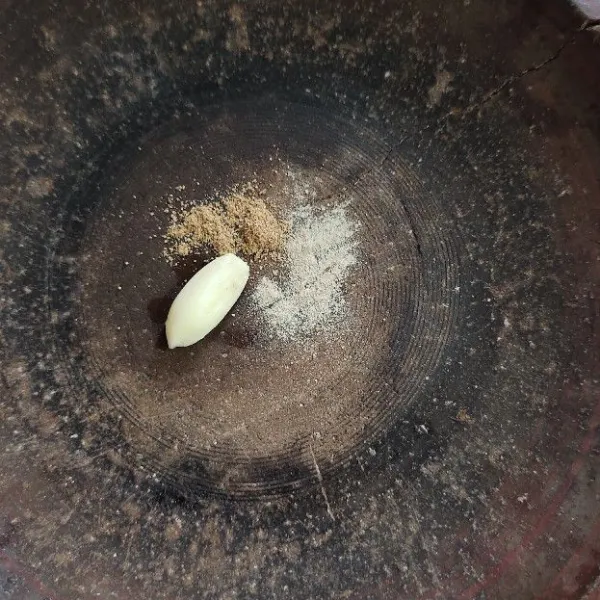 Masukkan bawang putih, ketumbar bubuk dan lada bubuk ke cobek.