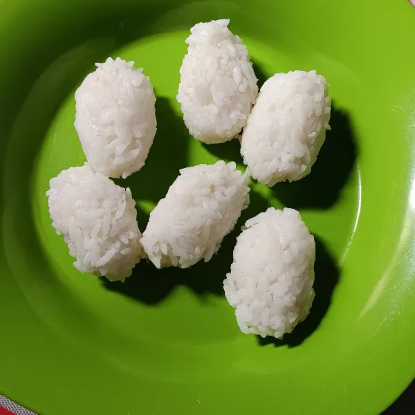 Siapkan nasi panas. Basahi tangan dengan air matang. Ambil sesendok penuh nasi kemudian kepal. Lakukan sampai selesai.