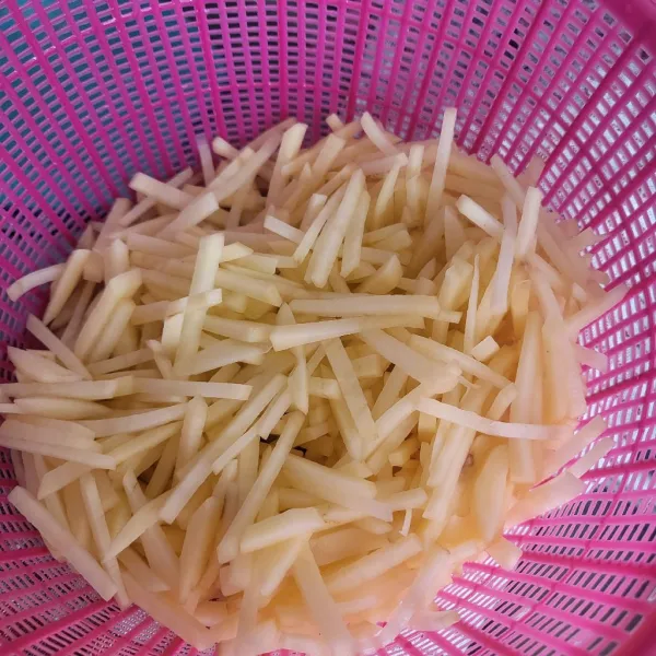 Potong-potong kentang berbentuk korek api tipis, kemudian cuci bersih, bilas beberapa kali hingga airnya bening.