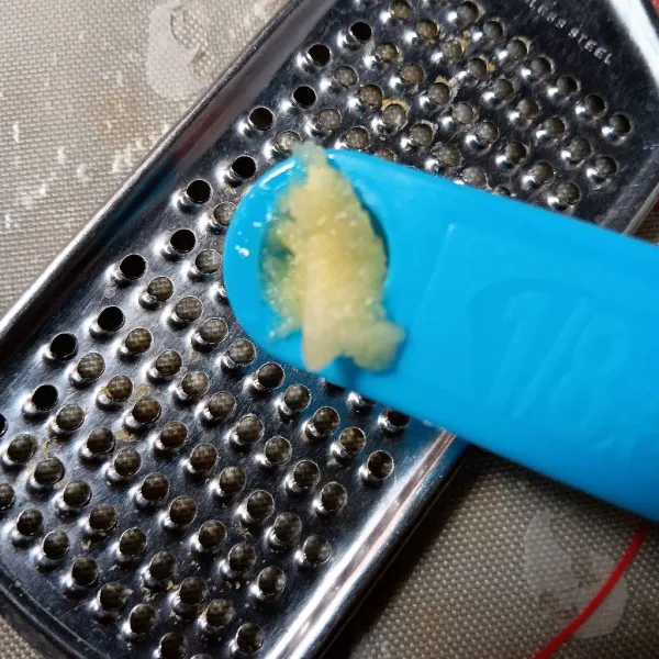 Parut halus bawang putih kemudian pindahkan ke mangkok.