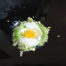 Pecahkan telur di tengah wajan. Goreng hingga setengah matang.