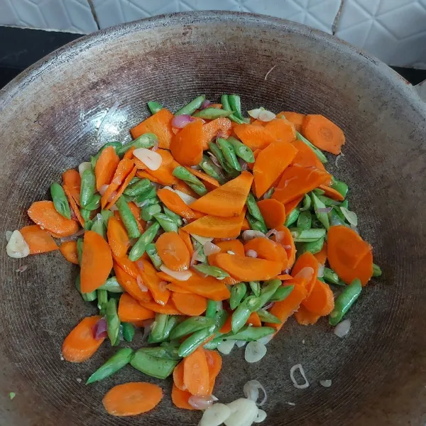 Masukkan sayur yang keras terlebih dahulu yaitu wortel, kemudian buncis. Aduk rata.